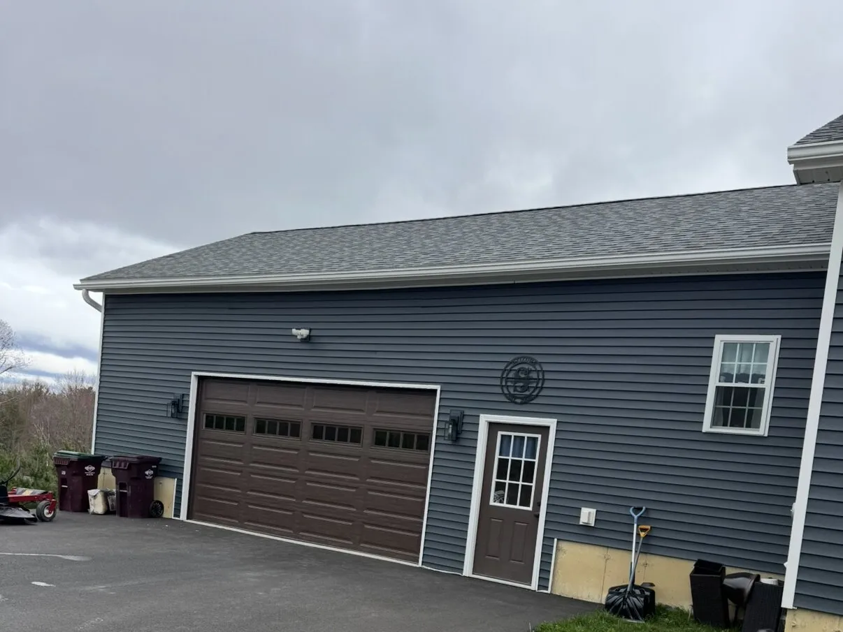 Brown long-panel garage door with a matching entry door on a navy-sided garage
