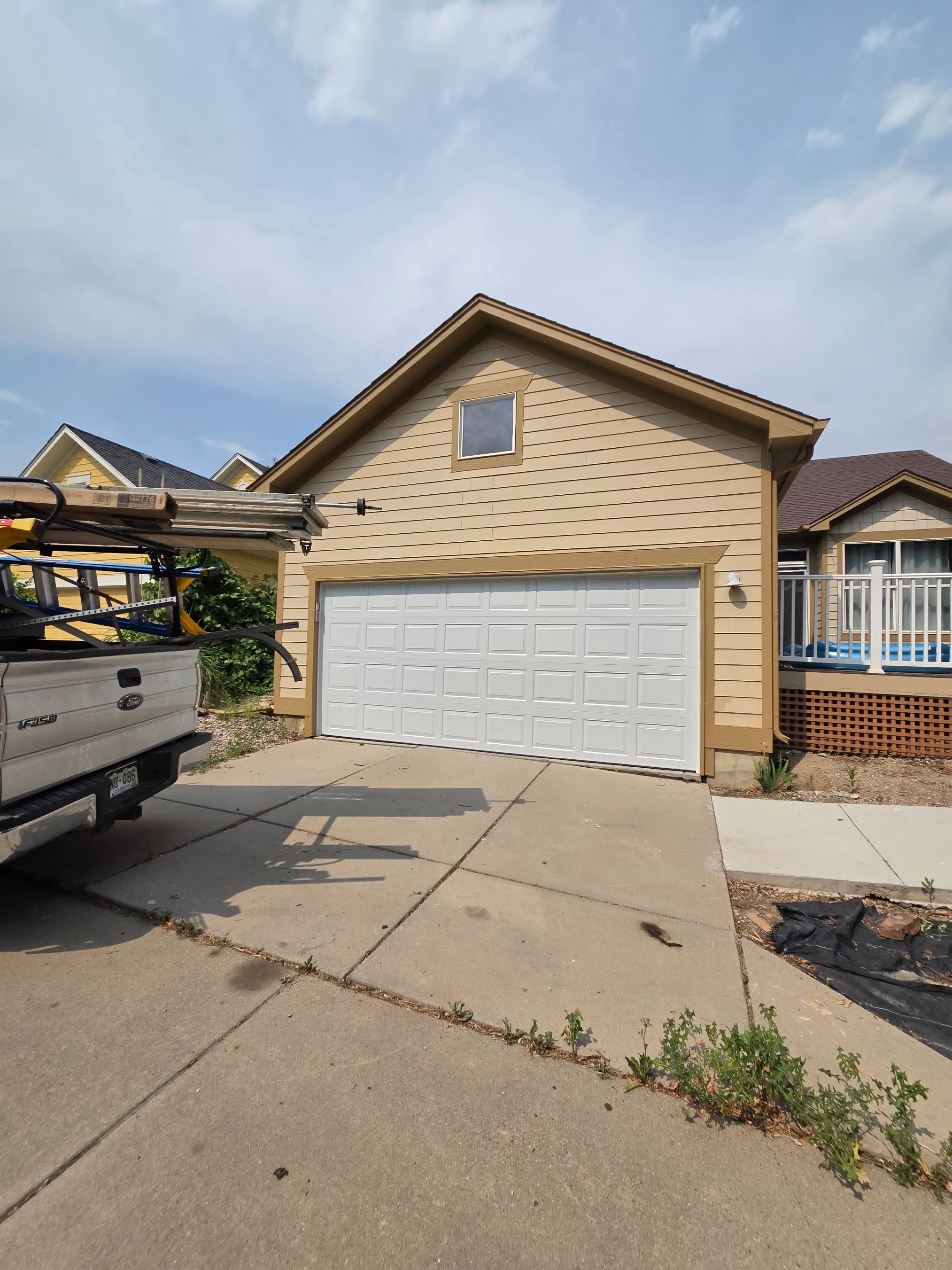 Service truck carrying garage door track parked at a home during a door installation