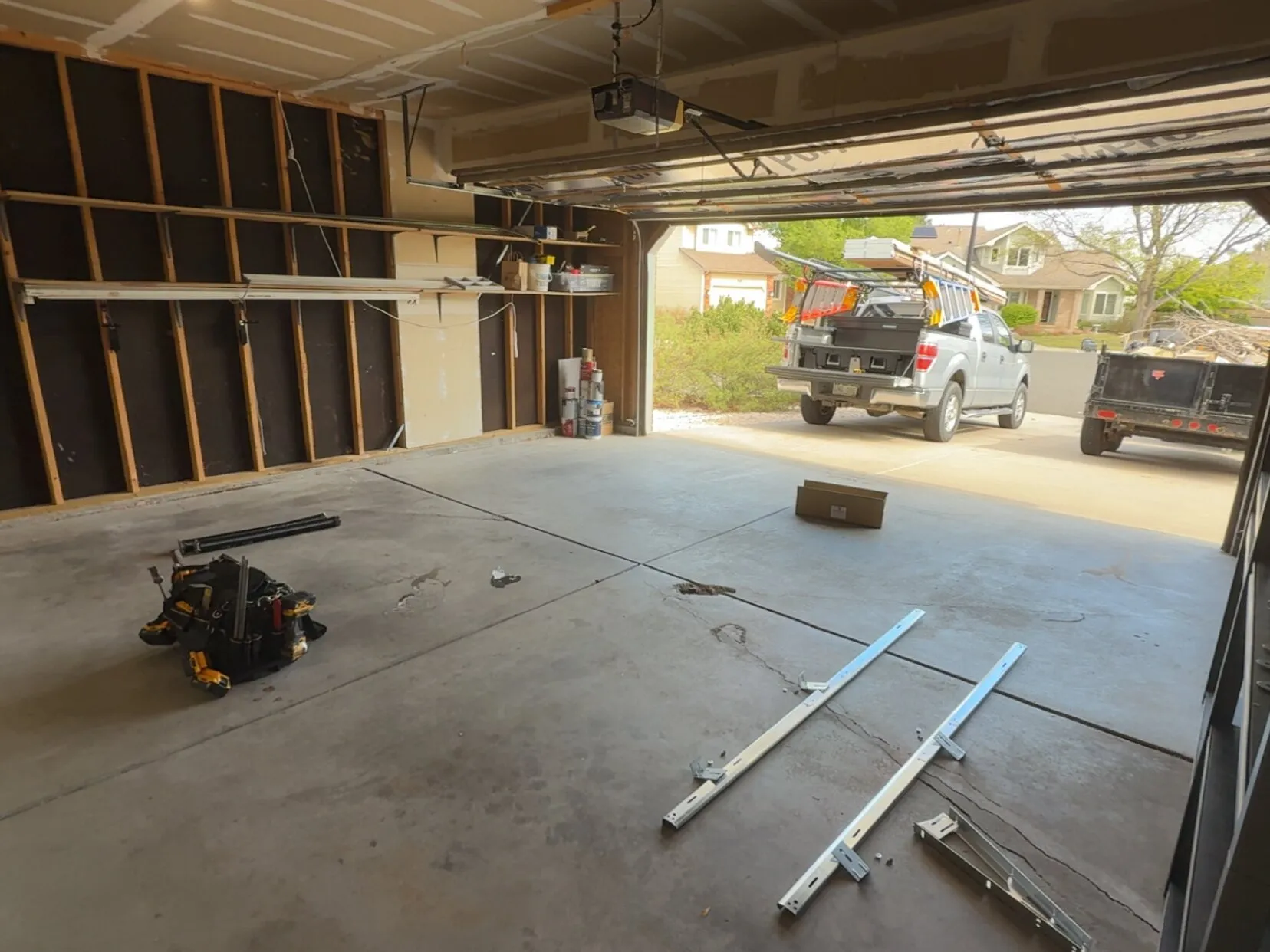 Garage door opener installation in progress, with the new rails laid out on the floor and the opener mounted overhead