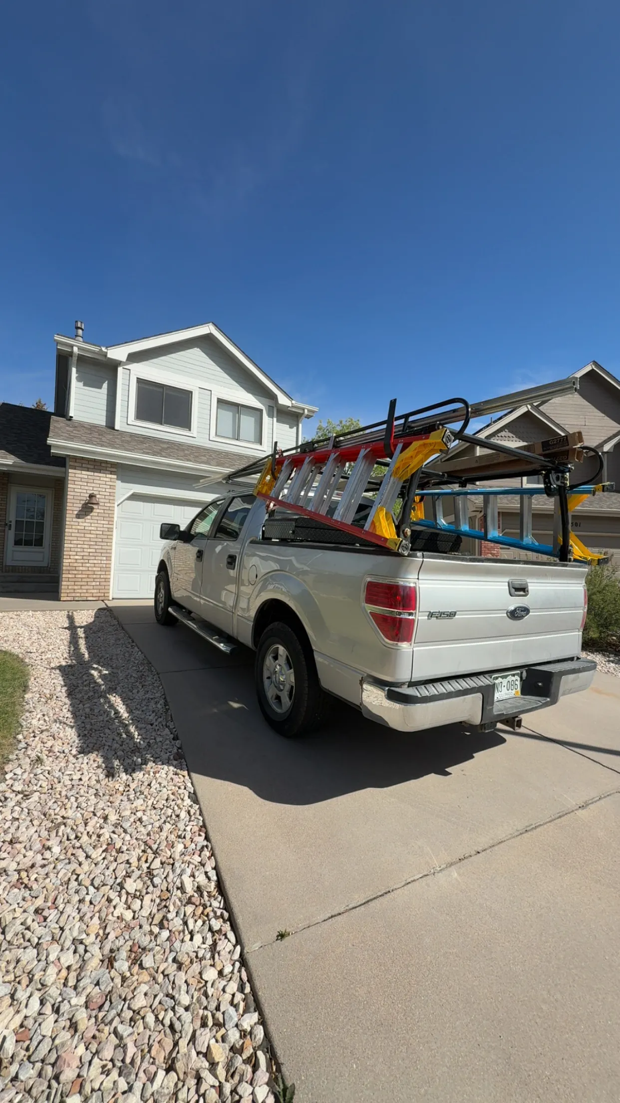 Nelson Overhead Door service truck loaded with ladders and garage door track, parked at a Colorado job