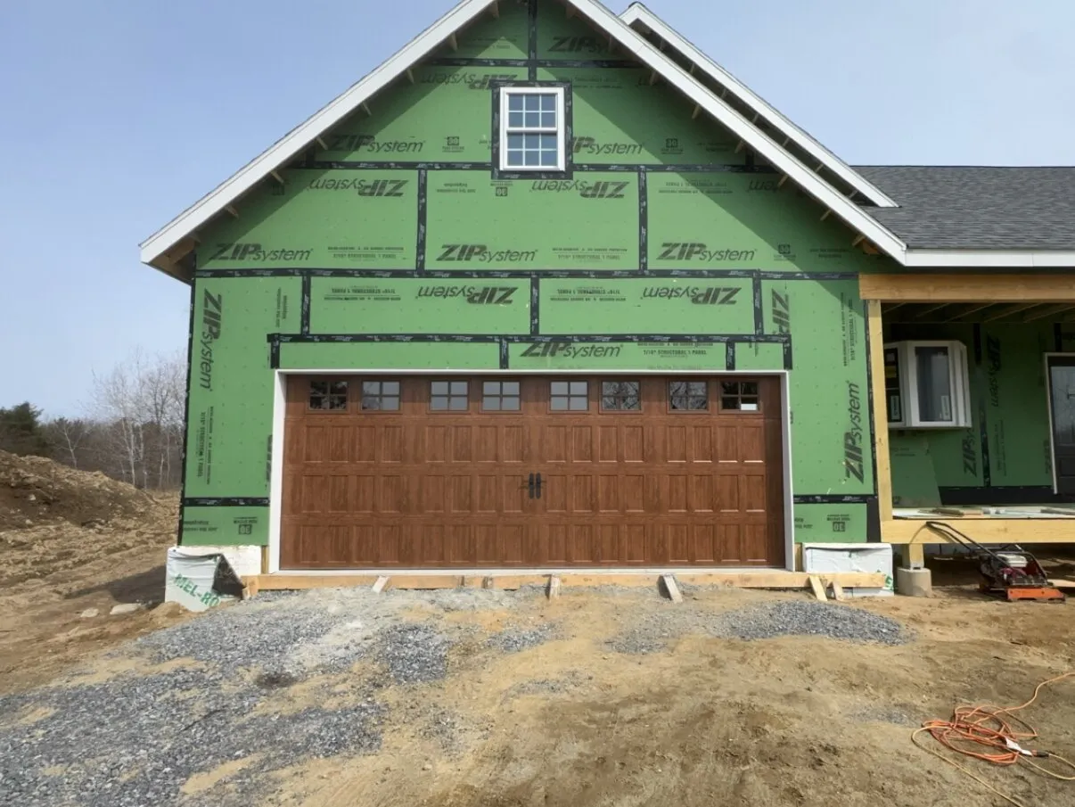 Oak carriage-style garage door fitted on a new-construction home still in structural sheathing