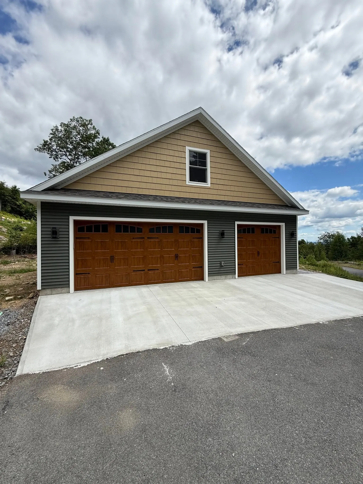 Detached three-car garage with oak carriage-style doors, seen from the driveway
