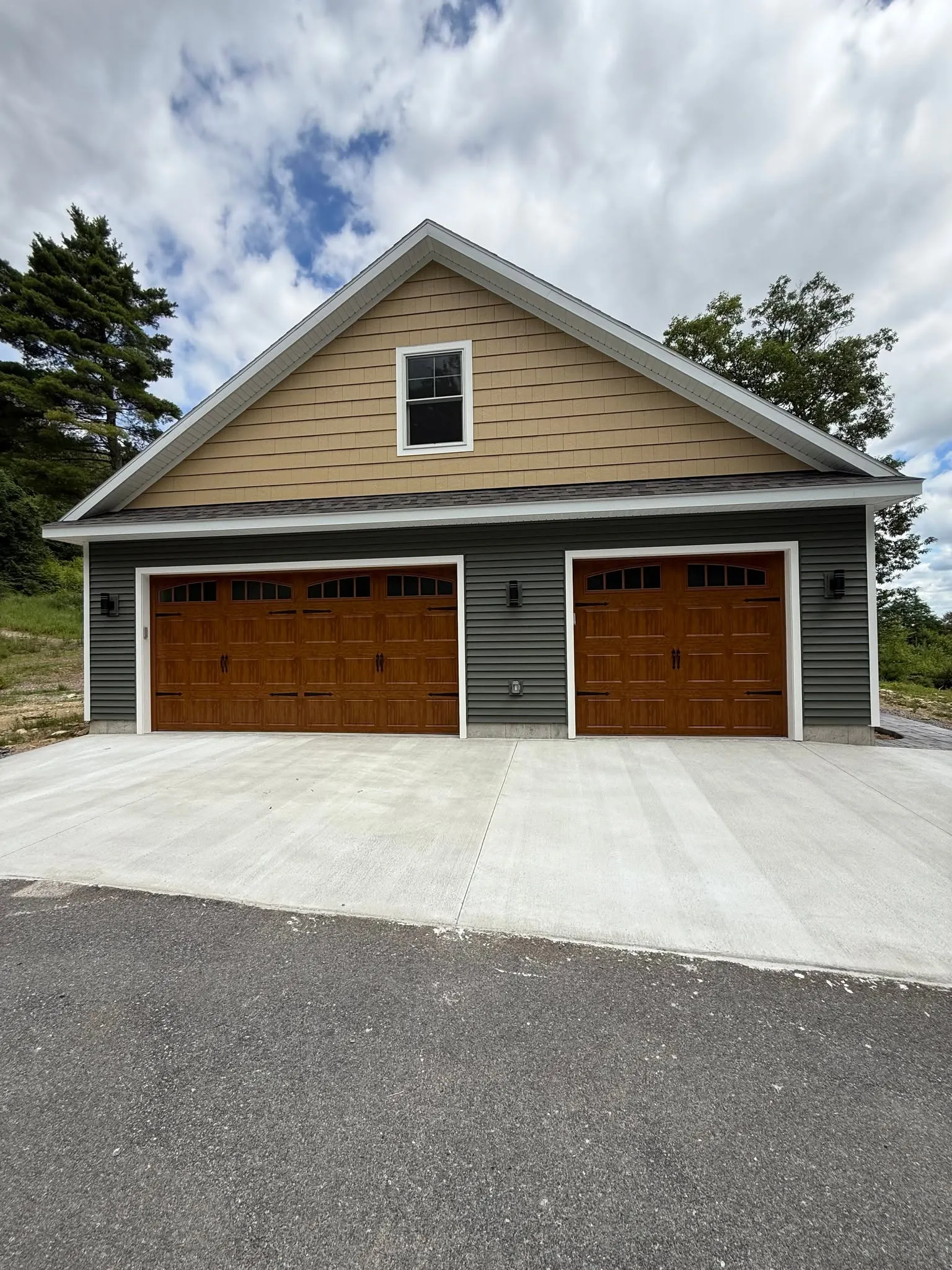 Three oak carriage-style garage doors with arched window lites on a detached three-car garage