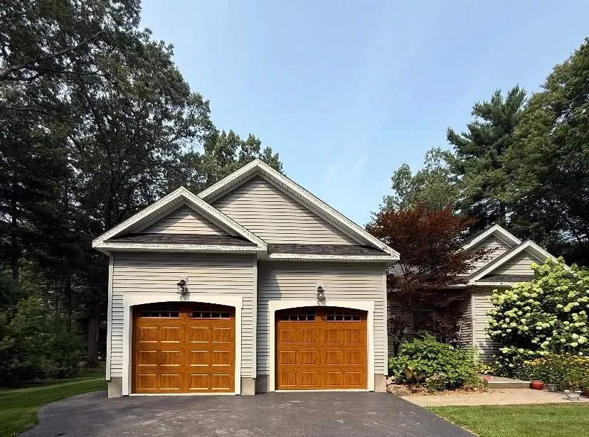 Two single-bay oak carriage-style garage doors on a cream-sided home