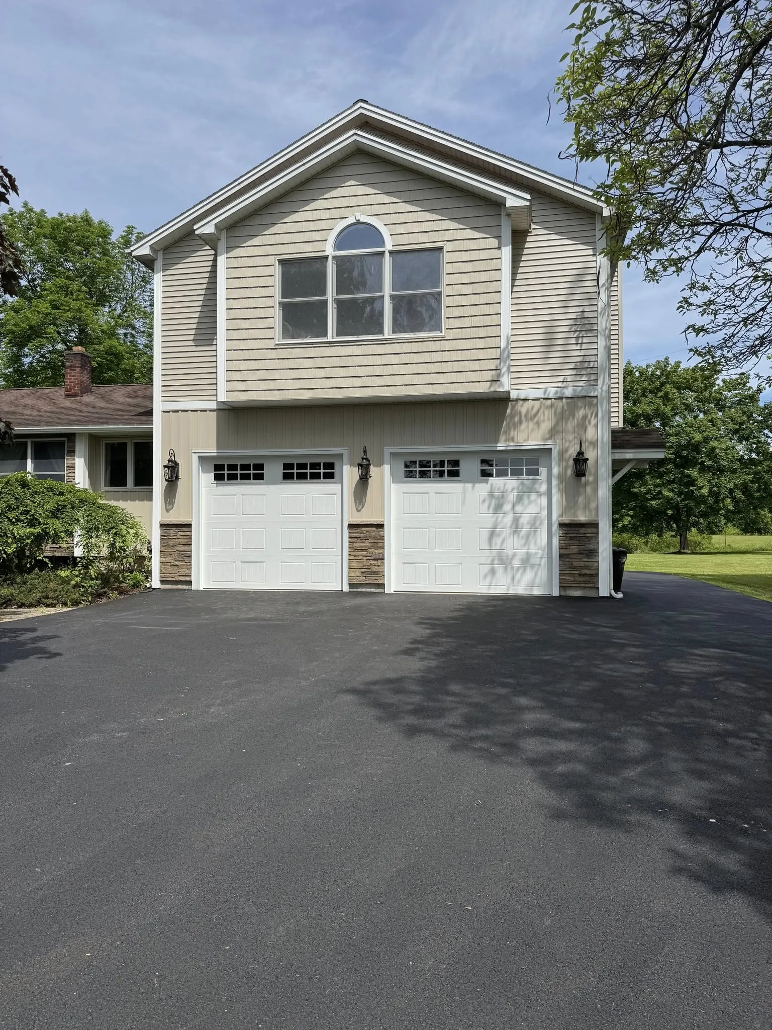 Two white carriage-style garage doors with top window lites on a two-storey home